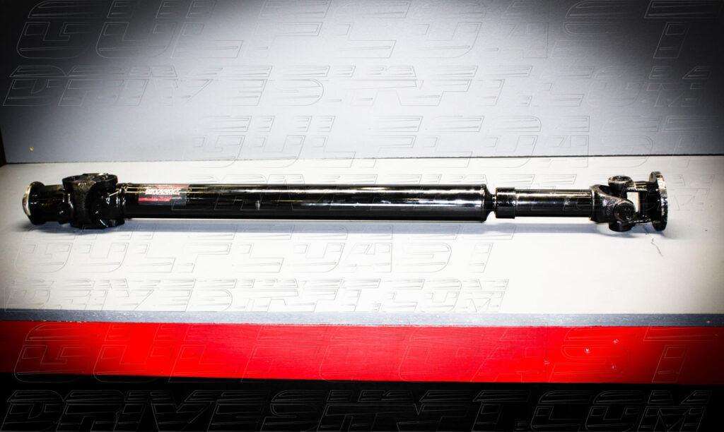 Black 1310 series rear driveshaft for 2018+ Jeep JL Wrangler, featuring solid U-joints and a pinion flange, displayed on a gray background.