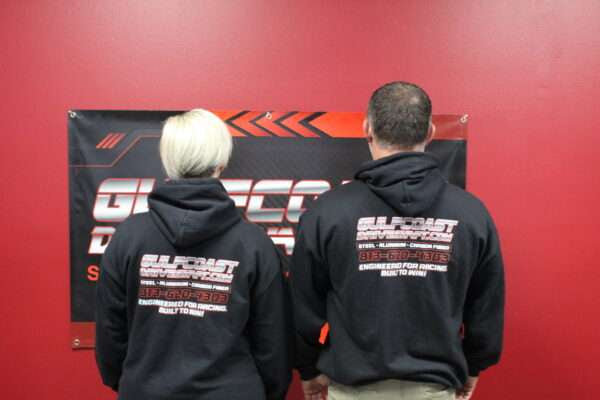 Black Gulf Coast Driveshaft hoodie shirts displayed on two people, featuring the logo and text on the back in white and red.